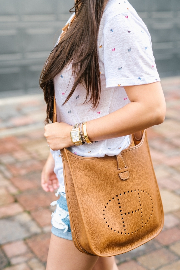 Luxury Handbag Collection and Review featured by top US fashion blog, LuxMommy: image of a woman wearing a Hermes Evelyne PM Gold