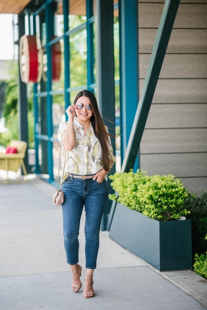 White House Black Market Summer Collection Favorites featured by top US fashion blog, LuxMommy: image of a woman wearing a White House Black Market leaf button down shirt, high rise skinny crop jeans, aviator sunglasses, hoop earrings, bangle bracelets, and cuff bracelet