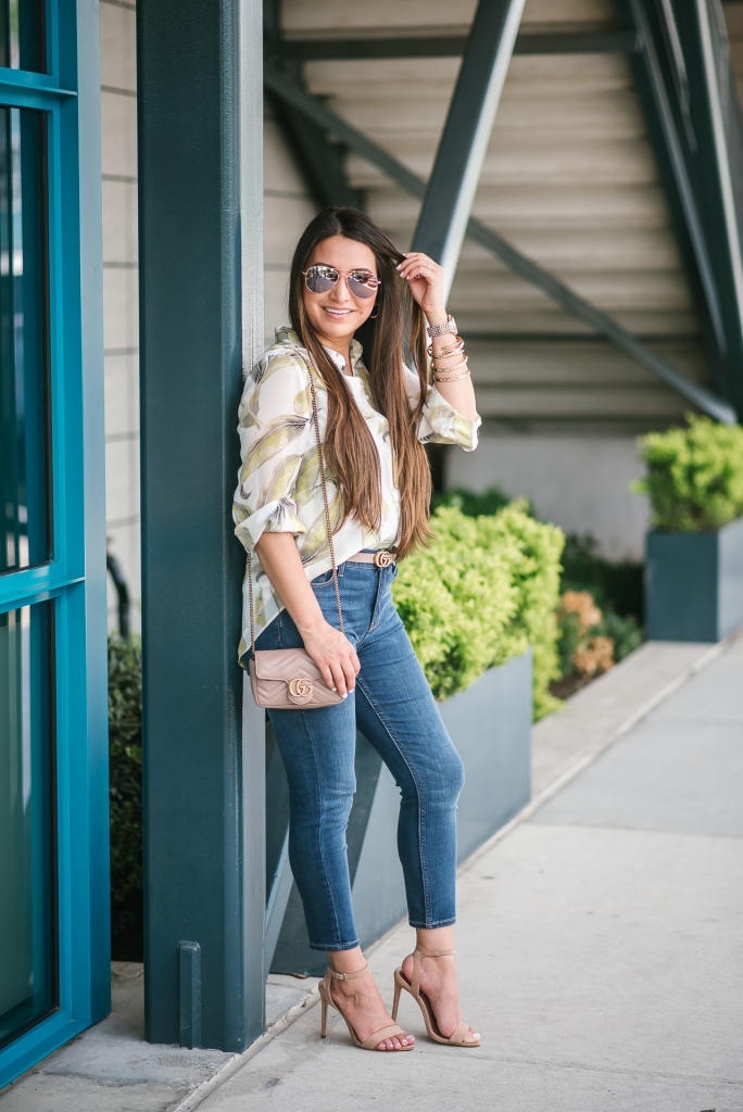 White House Black Market Summer Collection Favorites featured by top US fashion blog, LuxMommy: image of a woman wearing a White House Black Market leaf button down shirt, high rise skinny crop jeans, aviator sunglasses, hoop earrings, bangle bracelets, and cuff bracelet