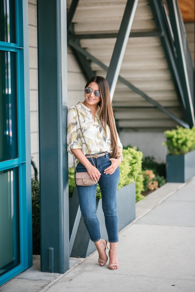 White House Black Market Summer Collection Favorites featured by top US fashion blog, LuxMommy: image of a woman wearing a White House Black Market leaf button down shirt, high rise skinny crop jeans, aviator sunglasses, hoop earrings, bangle bracelets, and cuff bracelet