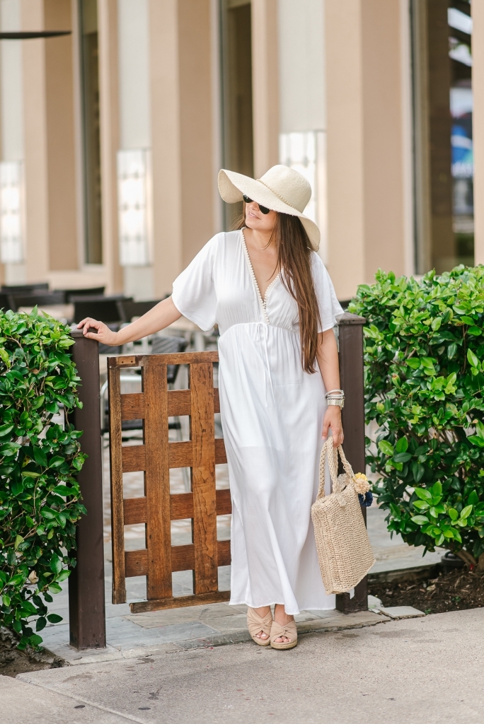 Cute Walmart summer dresses featured by top US fashion blog, LuxMommy: image of a woman wearing an LA Gypsy white maxi dress, Eliza May Rose straw hat, Eliza May Rose pom bag, Michele gold watch, POP fashioner aviator sunglasses and Sam Edelman wedge espadrilles