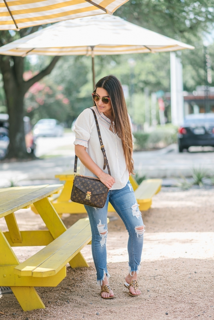 Rainbow smocked top styled for summer by top US fashion blog, LuxMommy: image of a woman wearing a Madewell rainbow smocked top, Express mid rise jeans, Tory Burch flip flops, Kendra Scott drop earrings, Michele diamond watch, Stella & Dot spike bracelet and Louis Vuitton crossbody bag.