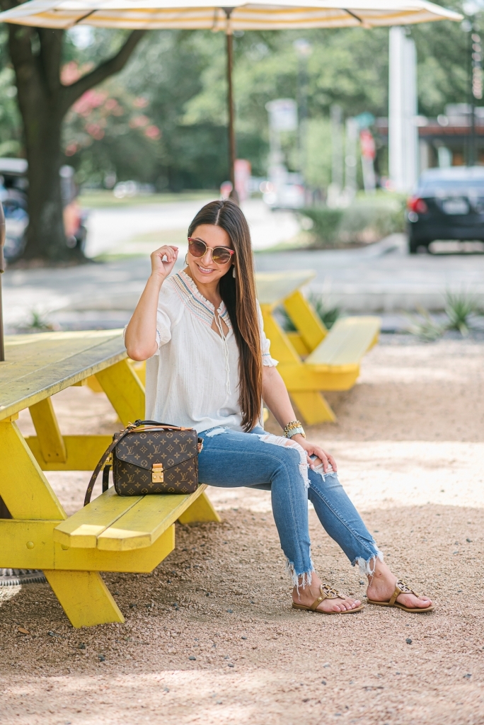 Rainbow smocked top styled for summer by top US fashion blog, LuxMommy: image of a woman wearing a Madewell rainbow smocked top, Express mid rise jeans, Tory Burch flip flops, Kendra Scott drop earrings, Michele diamond watch, Stella & Dot spike bracelet and Louis Vuitton crossbody bag.