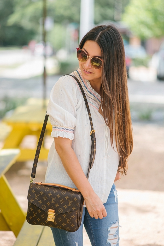 Rainbow smocked top styled for summer by top US fashion blog, LuxMommy: image of a woman wearing a Madewell rainbow smocked top, Express mid rise jeans, Tory Burch flip flops, Kendra Scott drop earrings, Michele diamond watch, Stella & Dot spike bracelet and Louis Vuitton crossbody bag.