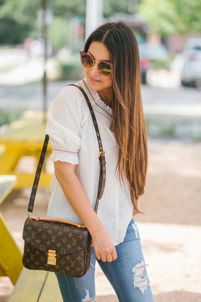 Rainbow smocked top styled for summer by top US fashion blog, LuxMommy: image of a woman wearing a Madewell rainbow smocked top, Express mid rise jeans, Tory Burch flip flops, Kendra Scott drop earrings, Michele diamond watch, Stella & Dot spike bracelet and Louis Vuitton crossbody bag.