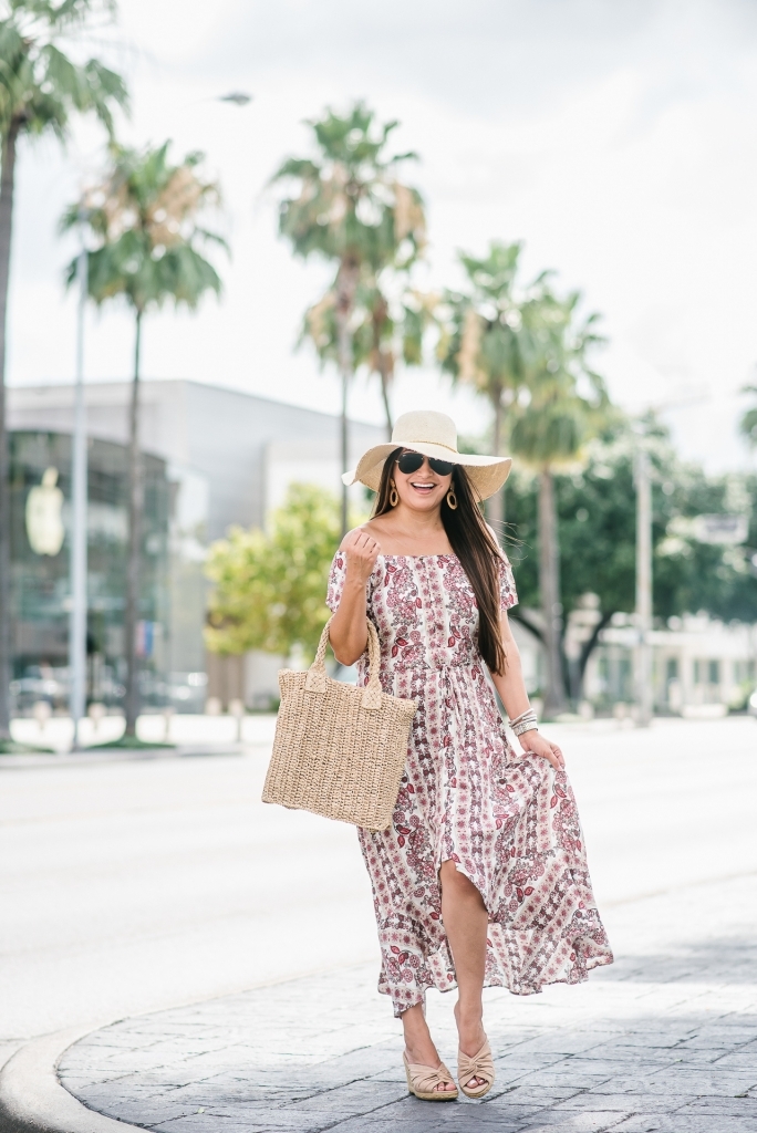 Affordable Summer Dresses featured by top US fashion blog, LuxMommy: image of a woman wearing a Cherokee floral hi low dress, Eliza May Rose straw sunhat, Eliza May Rose pom bag, Sam Edelman wedge espadrilles, Quay Australia studded aviator sunglasses, Michele diamond watch, and a David Yurman bracelet.