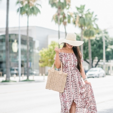 Affordable Summer Dresses featured by top US fashion blog, LuxMommy: image of a woman wearing a Cherokee floral hi low dress, Eliza May Rose straw sunhat, Eliza May Rose pom bag, Sam Edelman wedge espadrilles, Quay Australia studded aviator sunglasses, Michele diamond watch, and a David Yurman bracelet.