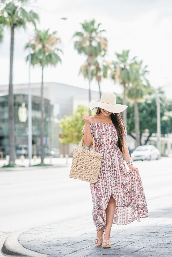 Affordable Summer Dresses featured by top US fashion blog, LuxMommy: image of a woman wearing a Cherokee floral hi low dress, Eliza May Rose straw sunhat, Eliza May Rose pom bag, Sam Edelman wedge espadrilles, Quay Australia studded aviator sunglasses, Michele diamond watch, and a David Yurman bracelet.