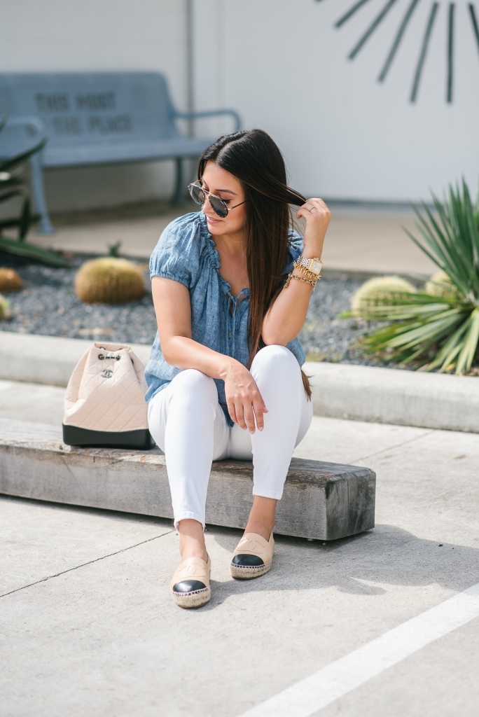 Chanel Gabrielle Backpack review featured by top US fashion blog, LuxMommy: image of a woman wearing a Chanel Gabrielle Backpack, Tory Burch cap toe flat, NYDJ chambray top, Quay Australia studded sunglasses, Michele diamond two tone watch, Stella & Dot bracelet, and a Kendra Scott charm bracelet.