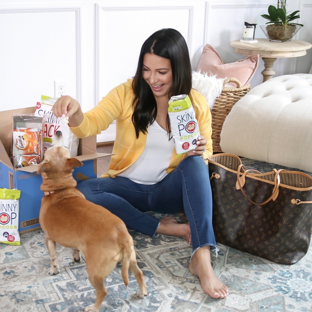 How to Get Household Essentials with Walmart Next Day Delivery by popular Texas life and style blog: Lux Mommy: image of a woman sitting on her floor, holding a bag of Skinny Pop and feeding it to her dog.