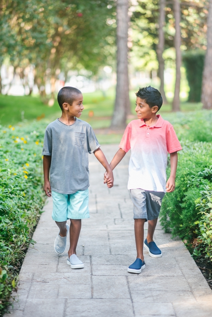 Back to School Style with Walmart by popular Texas fashion blog, Lux Mommy: image of two boys holding hand and walking on a brick pathway outside and wearing a Walmart Wonder Nation Short Sleeve Ombre Jersey Polo, The Children's Place Pull On Woven Jogger Short, and Crocs Unisex Junior CitiLane Roka Shoes.