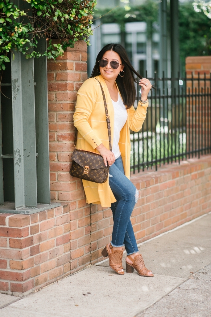 Affordable Fall Transitional Outfit by popular Texas fashion blog, Lux Mommy: image of a woman leaning up against a brick building and wearing a Walmart Heart N Crush Women's Long Striped Cardigan, Clementine Apparel Women's Deep V-Neck Short Sleeve T-Shirt, Sofia Jeans by Sofia Vergara Sofía Skinny Destructed Mid Rise Ankle Jean Women's (Medium Wash), and Women Big Buddha Woven Peep Toe shoe.