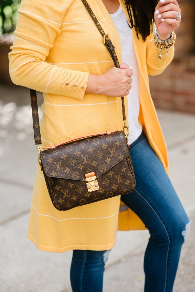 Affordable Fall Transitional Outfit by popular Texas fashion blog, Lux Mommy: image of a woman leaning up against a brick building and wearing a Walmart Heart N Crush Women's Long Striped Cardigan, Clementine Apparel Women's Deep V-Neck Short Sleeve T-Shirt, Sofia Jeans by Sofia Vergara Sofía Skinny Destructed Mid Rise Ankle Jean Women's (Medium Wash), and Women Big Buddha Woven Peep Toe shoe.